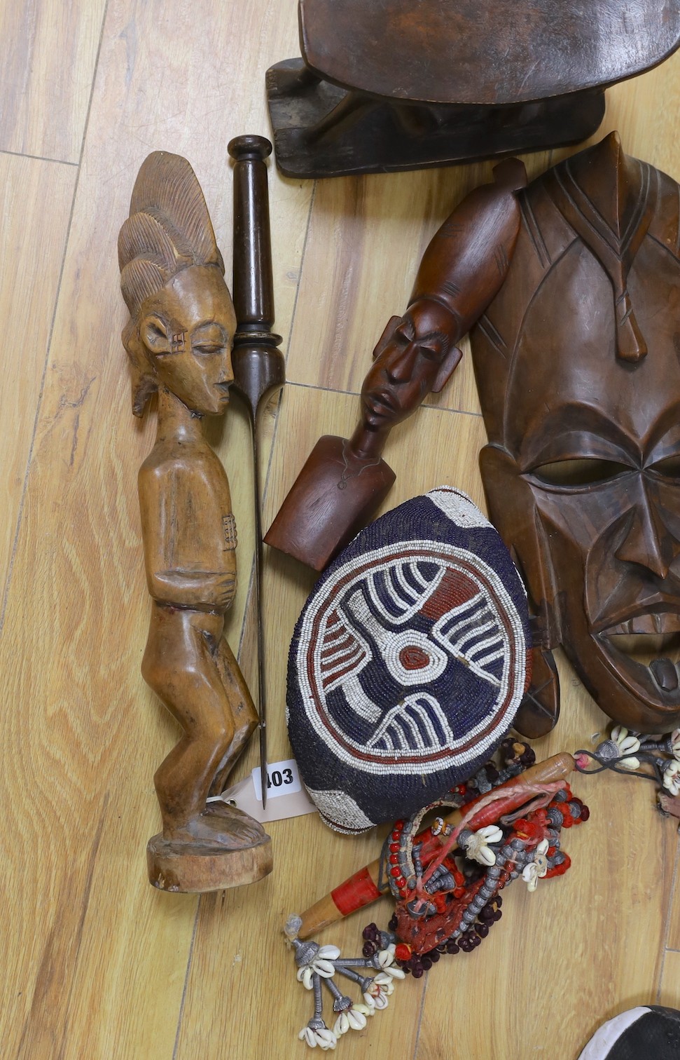 A group of African hardwood carvings, shell and beadwork including a cap